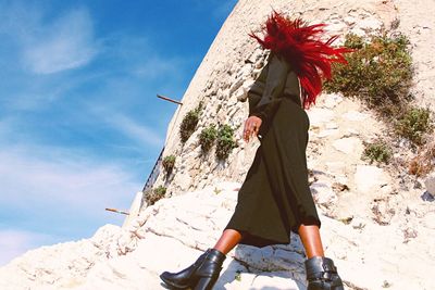 Low angle view of woman walking by wall against clear sky