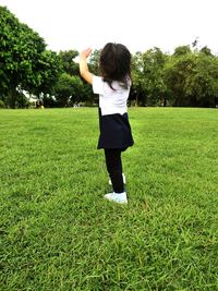 Full length of girl with arms raised standing on grass field