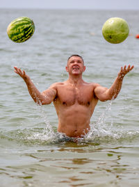 Full length of shirtless man with ball in water