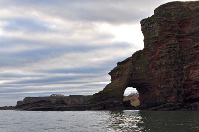 Rock formations by sea against sky