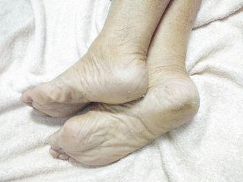 Close-up of human hand on bed