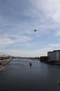 Airplane flying over london docklands against sky
