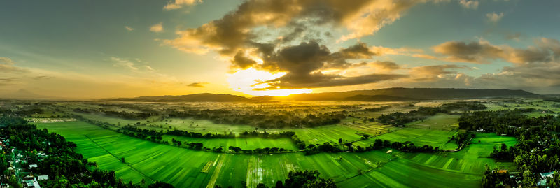 Panoramic shot of agricultural field against sky during sunset