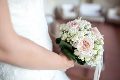 Midsection of bride holding flower bouquet