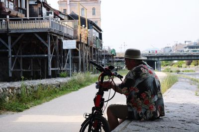 Rear view of man riding motorcycle on road in city