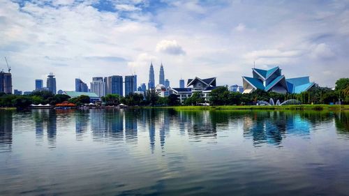 City at waterfront against cloudy sky