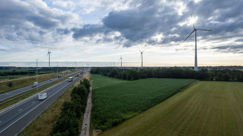 Panoramic view of wind farm or wind park, with the motorway with few cars and railroad next to it