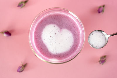 Pink rose milk with rose petals. adding heart-shaped foam to a glass of moon milk. healthy drink.