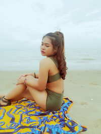 Beautiful young woman sitting on beach