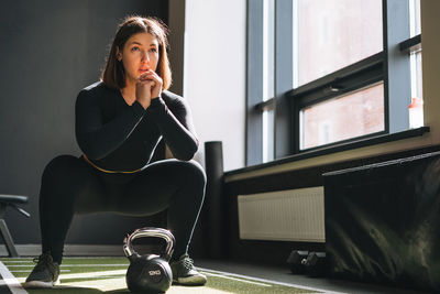 Young woman training her muscles with kettlebell in fitness club gym