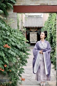 Young woman standing against plants