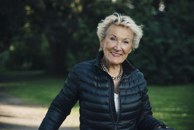 Portrait of happy senior woman wearing jacket in park