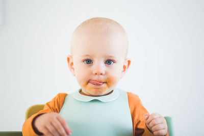 Portrait of baby girl licking messy mouth at home