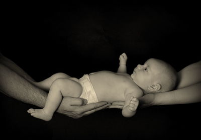 Close-up of baby hands against black background