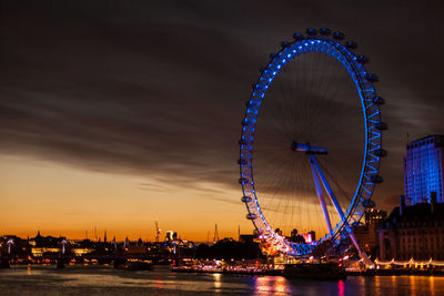 Ferris wheel in front of tower at night