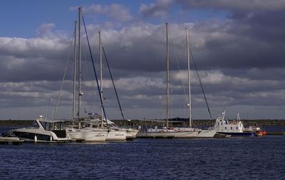 Sailboats moored in sea against sky