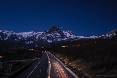 Light trails on road against clear sky at night