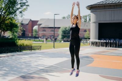 Full length of woman with arms raised jumping outdoors