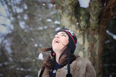 Happy woman wearing warm clothing looking up during winter