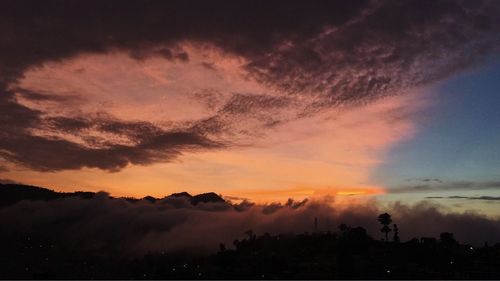 Silhouette trees and buildings against sky during sunset