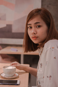 Portrait of woman with coffee cup on table