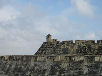 Low angle view of old building against cloudy sky