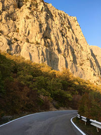 Road by rock formation against sky