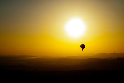Silhouette of balloon flying at sunset