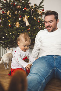 Portrait of smiling man with dog on christmas tree