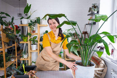 Portrait of smiling young woman standing against plants