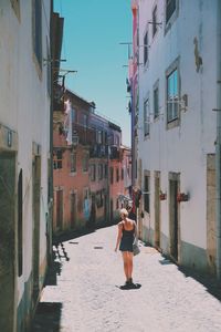 Rear view of woman walking on road in city