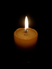 Close-up of illuminated tea light candle in darkroom