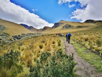 Rear view of people walking on mountain against sky