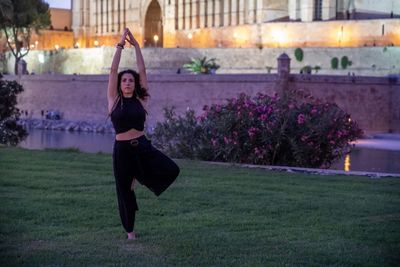 Full length of young woman practicing yoga on grass