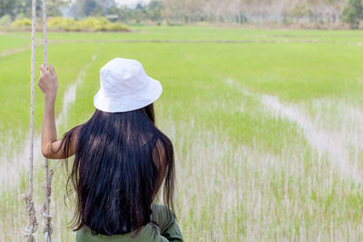 Rear view of woman sitting by rice field