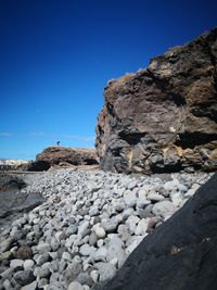 Rocks on shore against clear blue sky