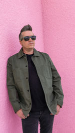 Portrait of young man standing against yellow wall