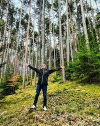 Full length of hiker standing on field in forest