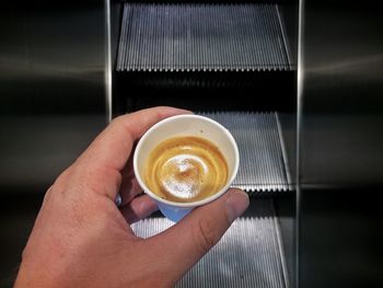 Cropped hand holding coffee on escalator