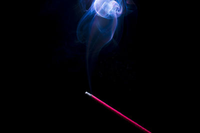 Incense and smoke against black background