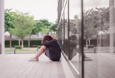 Side view of woman sitting on glass window