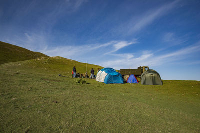 Men on camping on landscape against blue sky