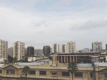 Buildings in city against cloudy sky