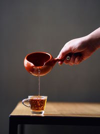 Midsection of person pouring wine in glass on table