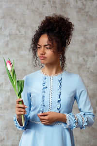 Woman looking at camera while standing against wall