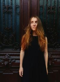 Beautiful young woman standing against door