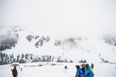 People skiing on snowcapped mountain against sky