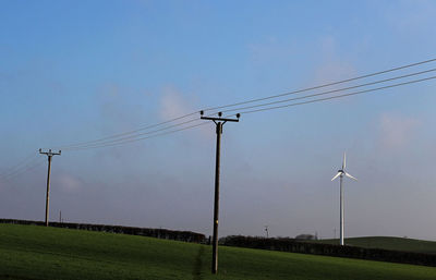 Electricity pylon on field against sky