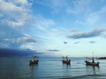 Sailboats moored in sea against sky