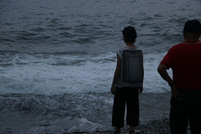 Rear view of men standing at beach